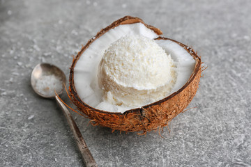 Fototapeta na wymiar Fresh ball of ice cream in half of coconut and spoon on grey background