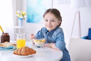 Cute little girl having breakfast at home