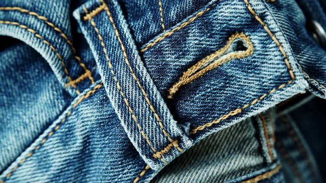 Closeup detail of blue denim jeans, texture background. Rack focus. Dolly sliding shot 4K ProRes HQ codec