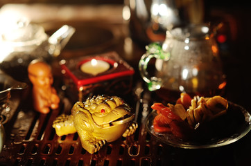 Clay three-toed tea toad with a coin in his mouth on the background of a tea table. Tea ceremony