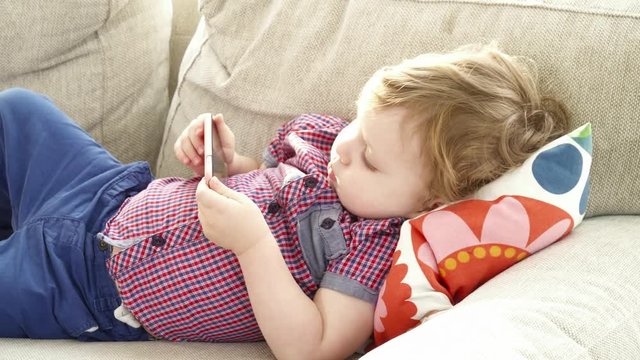 Cute baby boy watching cartoons on the smartphone