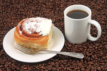 A white coffee cup with a pastry on a plat with fork on a background of coffee beans