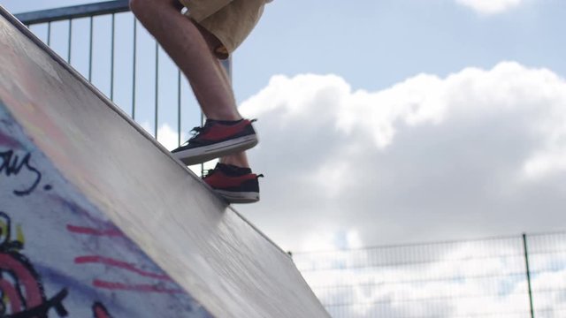 Skateboarder runs up a ramp before skating back down it, in slow motion 