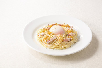 Spaghetti noodle pasta on white platter with egg