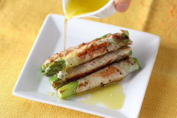 Asparagus beef rolls with oil on white platter