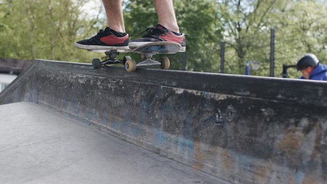 Skateboarder in a park performing a grind trick on a wall, in slow motion