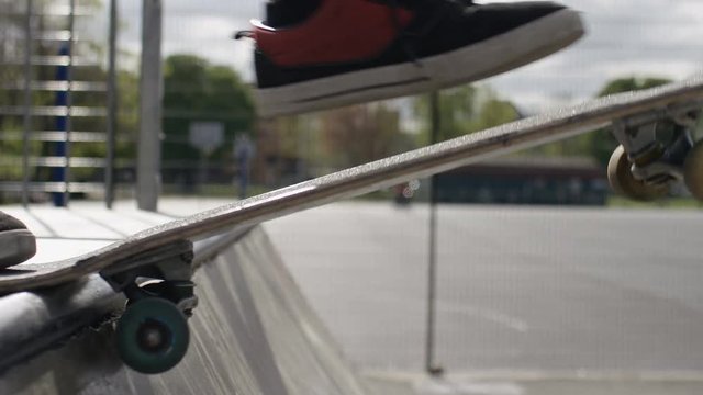 Close up of skateboarders feet mounting the board before descending a ramp, in slow motion