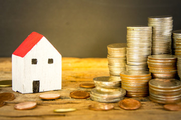 House and coins on the wooden table and black  background