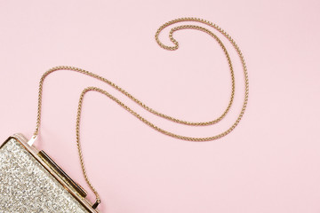 Festive evening golden clutch on pink. Holiday and celebration background. Luxury accessories and party concept