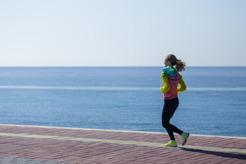 Sideview of young woman running by seaside