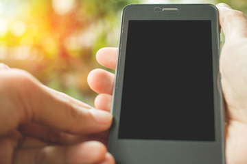 Close up of hands holding telephone with sunset background.
