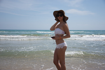 Fototapeta na wymiar Young woman in bikini at the beach of the sea on a sunny day