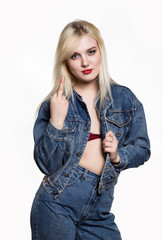 Sporty girl in denim jaket and jeans show middle finger, fuck you off sign on white background....