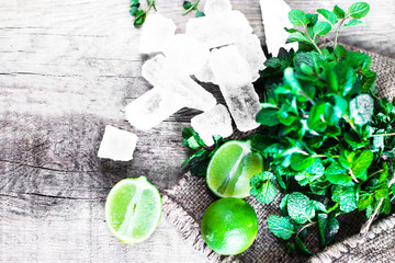 Mojito cocktail Ingredients - Fresh mint, limes, ice over wooden  backdrop. Top view, copy space