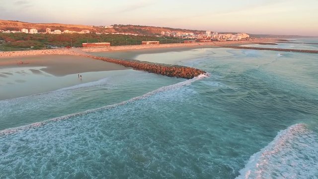Aerial videoin motion during sunset in the Atlantic Ocean in Costa da Caparica, Lisbon, Portugal.