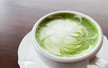 Closeup cup of hot matcha latte art on wood background