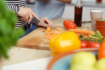 frau schneidet möhren auf einem holzbrett in der küche