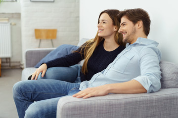 entspanntes paar sitzt auf dem sofa und schaut fern