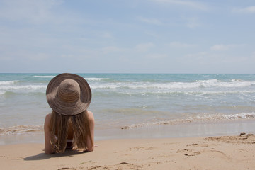 Fototapeta na wymiar Young woman in bikini at the beach of the sea on a sunny day