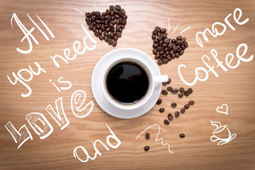 Hot cup of espresso and heart shape made from coffee beans on wooden surface. Sign: All you need is love and more coffee.