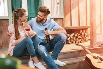 attractive woman and man resting with beer and wine on porch