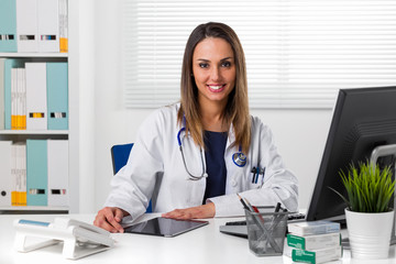 Smiling female doctor at desk using tablet