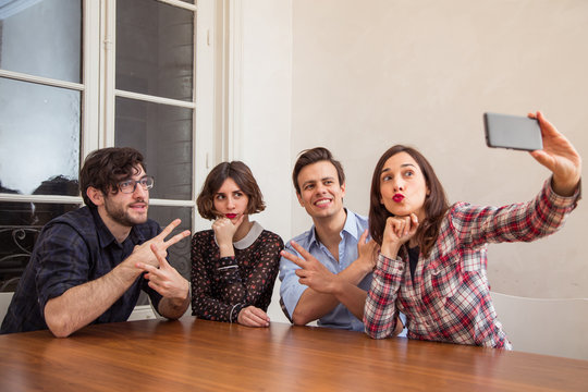 Four young cheerful friends taking selfie
