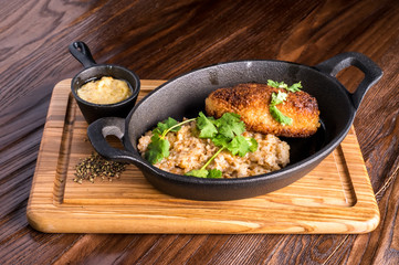 Buckwheat with patties in the frying pan on a wood