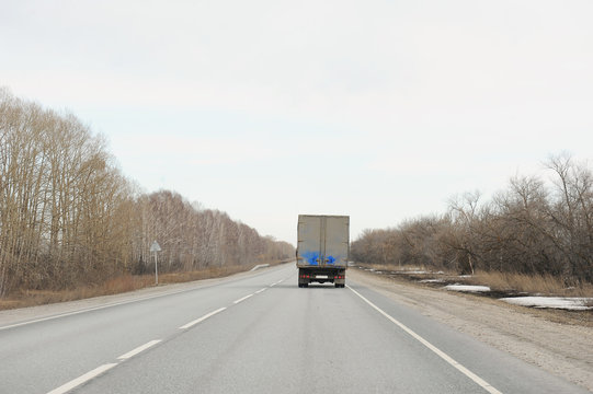 Ahead Of The Traveling Truck On The Highway. View From Behind The Walking Car