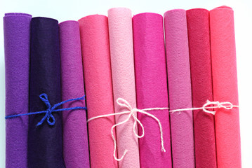 Pink and lilac felt in rolls on a white background.  hobby concept