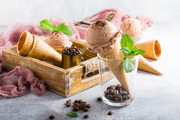 Homemade coffee ice cream in waffle cone on gray stone background. Healthy summer food concept with copy space.