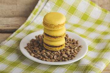 Yellow macarons on the plate with green coffee beans