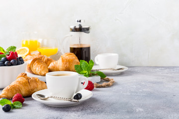 White cups of coffee and croissants on light gray background, selective focus. Healthy breakfast concept with copy space.