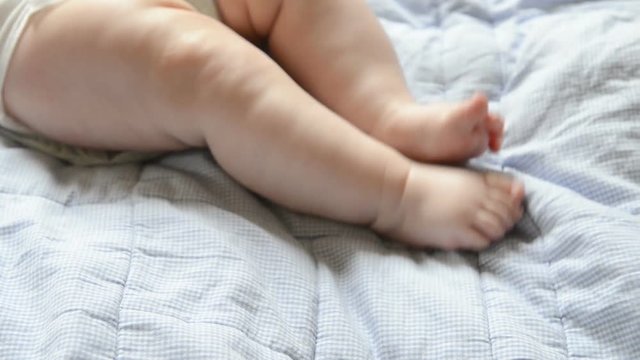 The baby moves with his feet, on a blue blanket