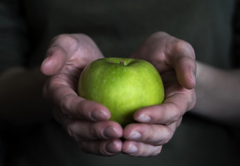Female hands holding a green juicy Apple.
