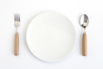 A white plate with fork and spoon on white background.