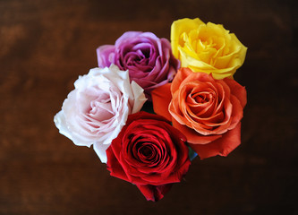 Bouquet of multicolored roses on a wooden brown background