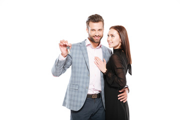 Happy young loving couple standing isolated holding keys.