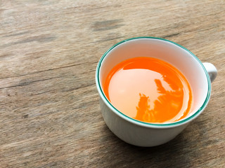 Tea cup on the wood table surface background.Orange juice in tea cup on wood table textured.
