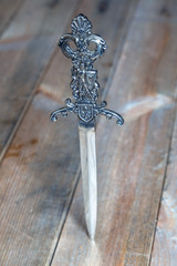 stiletto inlaid carved handle stuck into the wooden surface of the table
