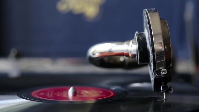 En macro le bras d'un gramophone qui tourne sur un vieux disque vinyl