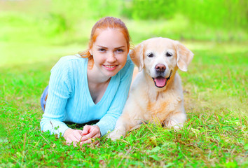 Portrait of happy smiling owner woman and Golden Retriever dog is lying on the grass summer