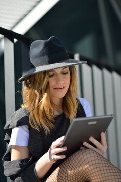 Young stylish female sitting with tablet