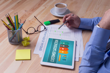 Man working on tablet with CUSTOMER SATISFACTION on a screen