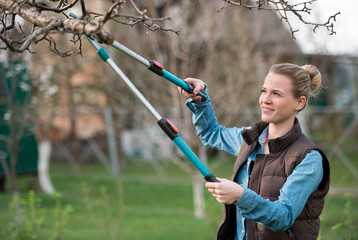 Girl gardener working in the spring garden and trimming tree