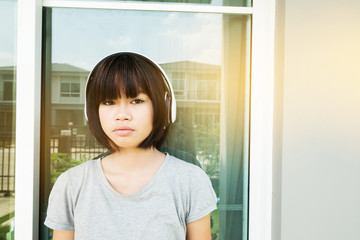 Young asian girl listen music with headphones at home.