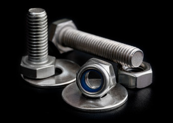 Steel bolts and nuts with washers on black background close-up