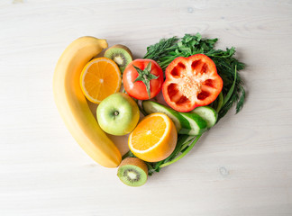 heart made from different fruits and vegetables on light wooden table