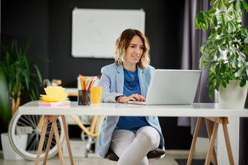 Freelancer using laptop computer while sitting in personal home office. Complementary colors used