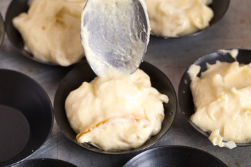 Taking muffin dough to baking pan.